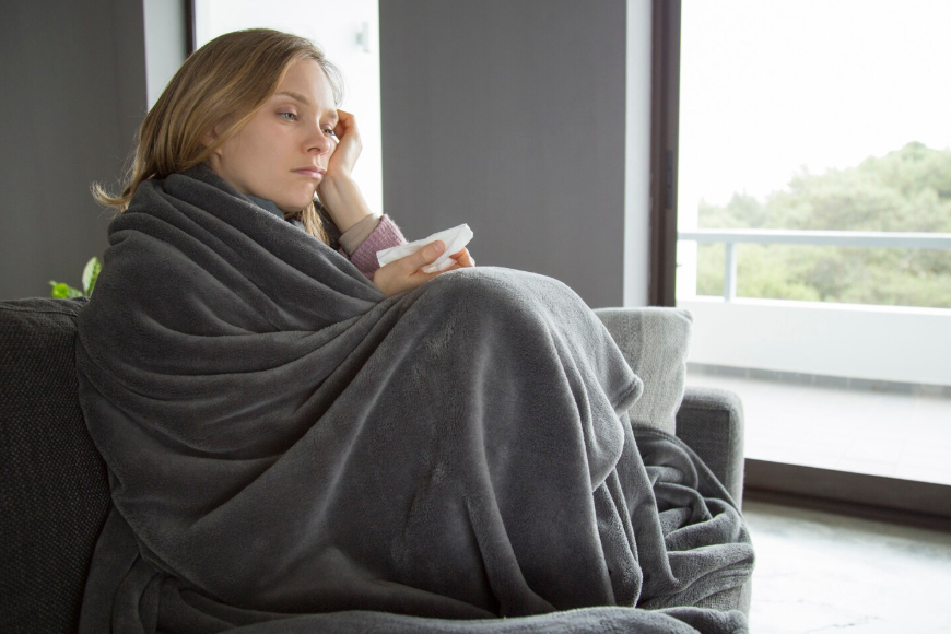 Person wrapped in a heated blanket showing why are heated blankets trending for warmth.