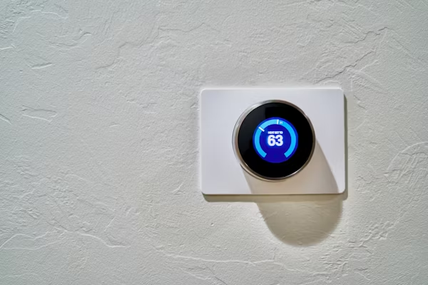 Smart thermostat displaying temperature on a home wall.