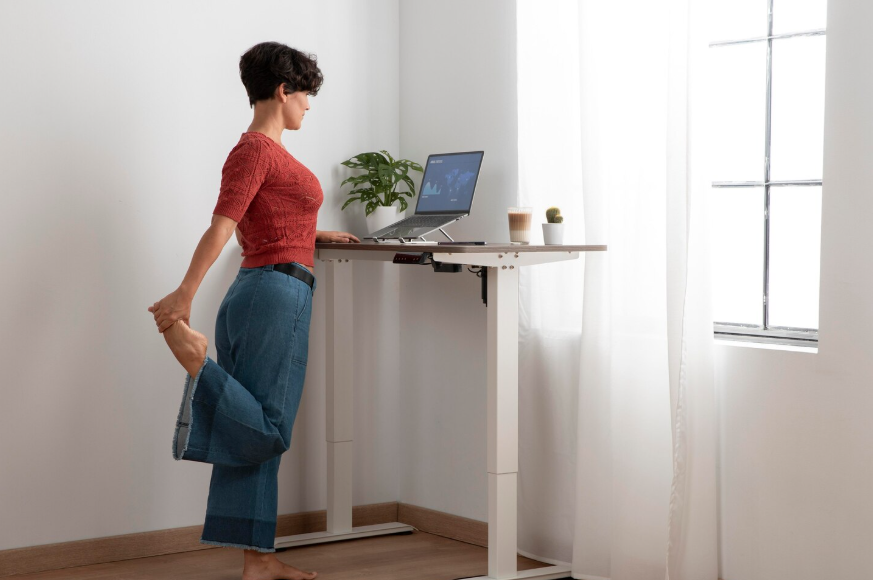 Person stretching while working at a standing desk in a home office.